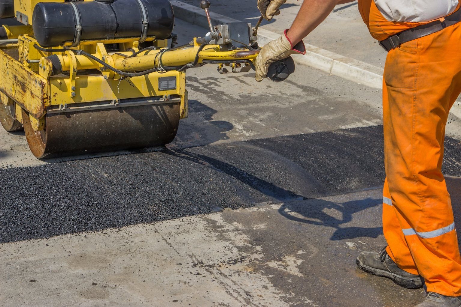 the contractor is smoothening the asphalt speed bump in this paved parking lot in Naples, FL